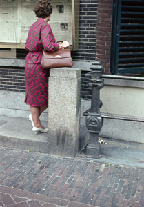 849847 Afbeelding van een vrouw die de krant leest in de vitrines van het het Kantoor van het Utrechts Nieuwsblad ...